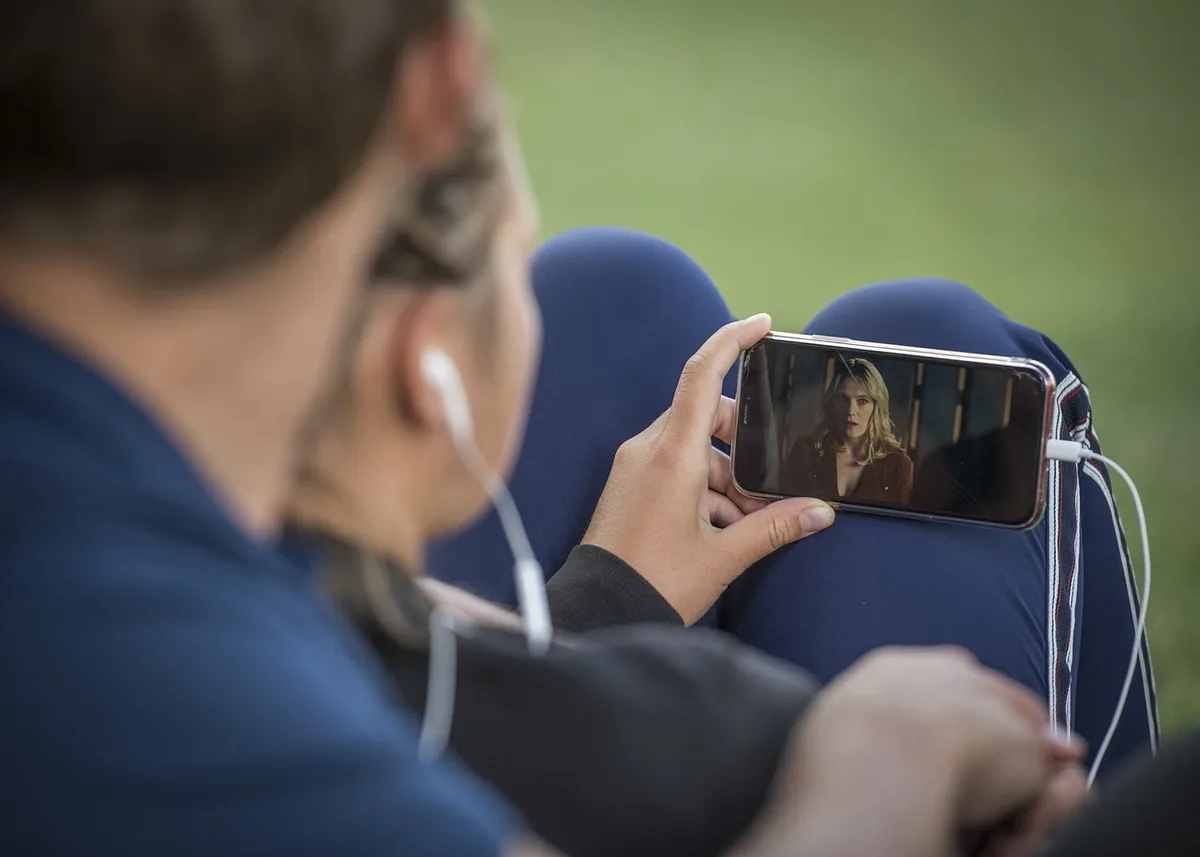 Person tapping export button on a mobile video editing app with progress bar visible.