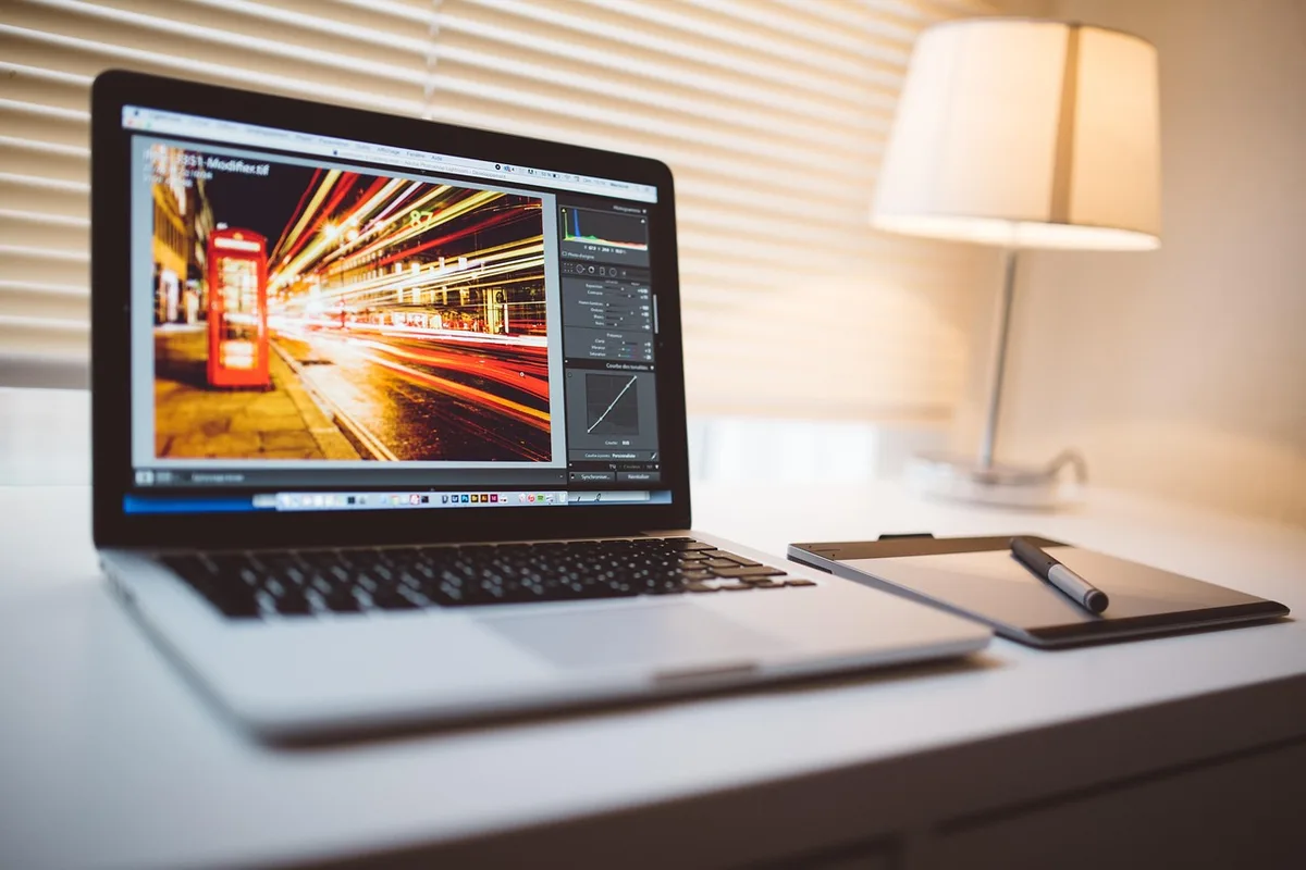A young person wearing headphones editing video on a laptop in a cozy room.