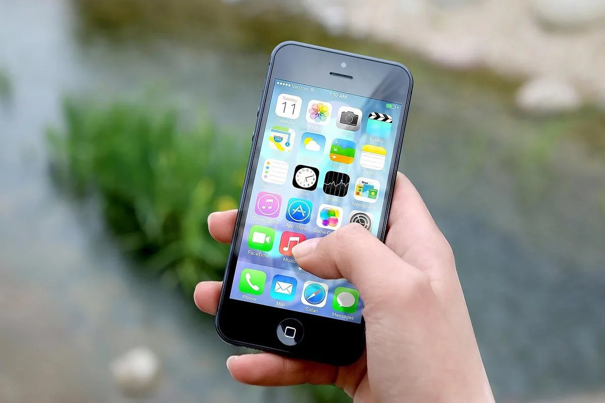 Person holding a smartphone displaying a video editing timeline with clips and effects.